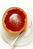 Rosa Grapefruithälfte mit Zucker auf Teller mit Löffel