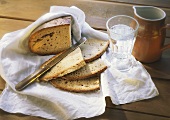 Bread, slices cut with knife on cloth, water glass and jug