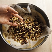 Placing beans on pastry for baking blind