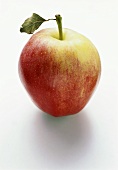 A yellow and red apple with leaf