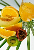 A glass of orange juice on palm leaf and fresh fruit