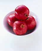 Four pomegranates on a white china plate