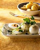 Eier mit Senf-Kapern-Sauce auf Platte, dahinter Kartoffeln