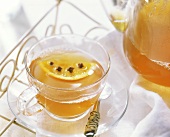 Citrus tea punch in glass cup and pot