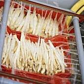 Asparagus being washed by machine in plastic boxes