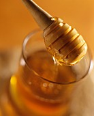 Honey running from honey spoon into a jar