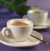 Two cups of espresso on blue background