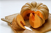 A cushaw pumpkin, cut into, lying on a board