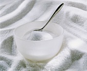 A bowl of sugar with spoon standing on sugar mountain