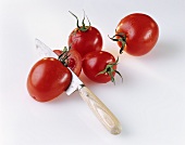 Several tomatoes (whole and cut) and knife
