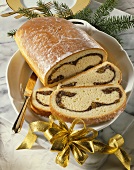 Poppy seed stollen on cake plate, partly sliced