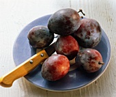 Plums on blue plate with knife