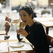 Junge Frau sitzt in Restaurant und isst Baguettesandwich