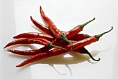Several red chili pepper against white backdrop