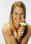 Junge blonde Frau hält Eistüte in der Hand