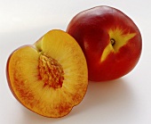 Half a nectarine with stone and a whole nectarine