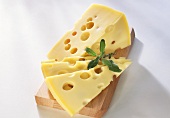 Emmental cheese in piece & in slices on wooden board