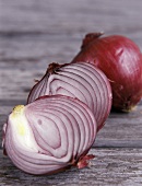 Red onion halves in front of a whole onion