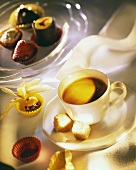 Cup of coffee with sugar lumps, home-made chocolates beside it