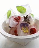 Ice cubes with fruit and flowers frozen in