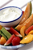 Sliced pieces of fruit and bowl of soft cheese spread