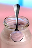 Strawberry yoghurt in yoghurt jar and on spoon