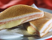 Two tramezzini with cheese and ham filling, toasted