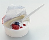 A pot of natural yoghurt with fresh berries and spoon