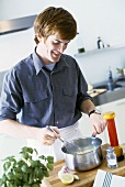 Young man stirring soup with whisk