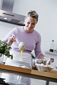 Young woman ladling soup into plate