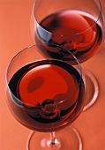 Two glasses of red wine on red background