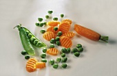 Pea pod and half carrot with peas and carrot slices
