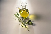 Olive oil in glass jug with olives and branch