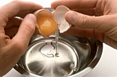 Separating egg yolk from white in egg shell and adding to bowl