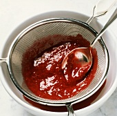 Straining raspberry sauce through a sieve