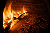 Pizzas in pizza oven with wood fire