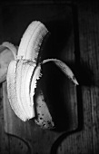 Eine geschälte Banane auf Holzbrettchen (s-w-Aufnahme)
