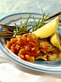 Fried catfish fillet with diced tomatoes and lemon wedges