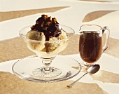 A bowl of ice cream with walnut & chocolate sauce & sauce jug