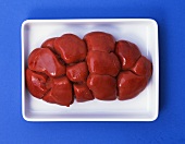 Veal kidney in white bowl on blue background