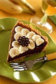 A piece of chocolate tart with banana slices on plate