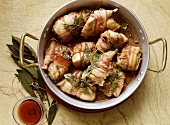 Braised rabbit pieces wrapped in bacon and bay leaf