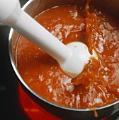 Blending pepper sauce to a puree with a hand blender