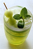 Melon drink with melon ball on cocktail stick and mint