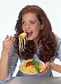 Red-haired woman eating spaghetti with tomato sauce