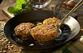 Green rye and vegetables cakes in the pan