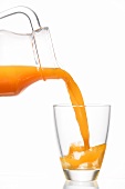Pouring multi-vitamin juice from a carafe into a glass