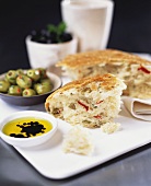 Oliven-Tomaten-Brot, daneben Olivenöl und Oliven