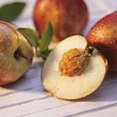 Half nectarine with stone in front of whole nectarines