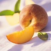 Peach wedge in front of whole peach